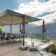 Cette image montre la terrasse élégante du restaurant "Les Mazots du Clos du Château", offrant une vue imprenable sur les vignes et la vallée de Sion.